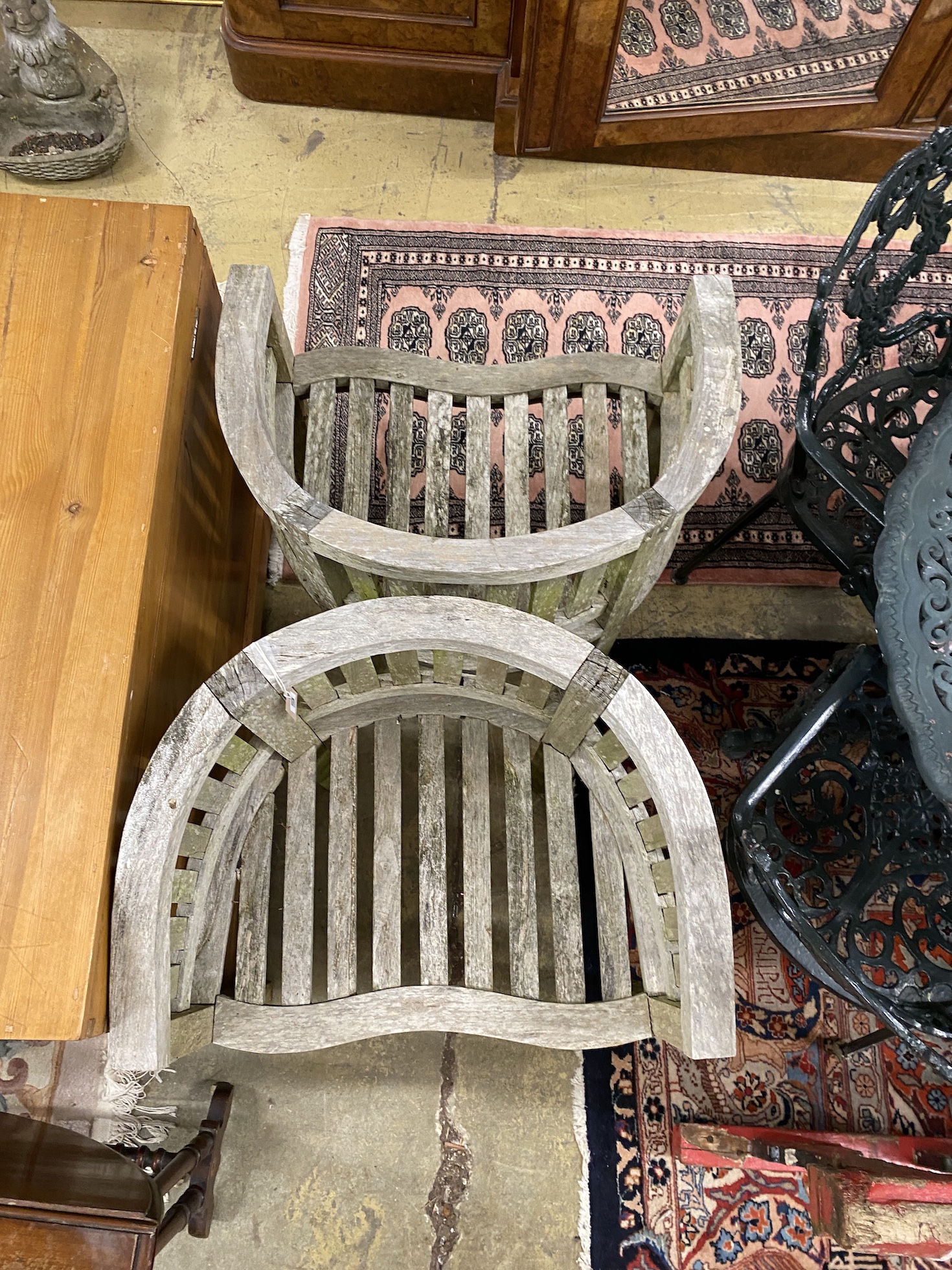 A pair of weathered teak tub shaped garden elbow chairs, width 67cm, depth 49cm, height 85cm